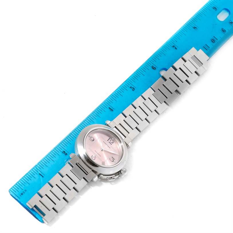 The image shows a top view of a Cartier Pasha W31075M7 Women's Stainless Steel Pink Dial W31075M7 Women's Stainless Steel Pink Dial watch with a metal bracelet next to a blue ruler for scale.