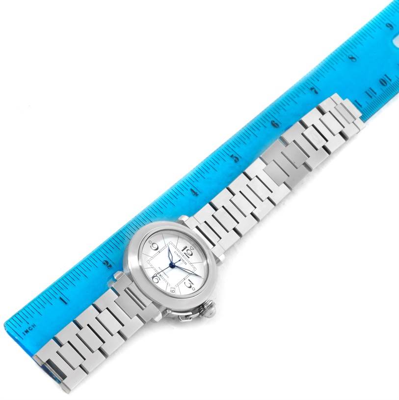 The Cartier Pasha W31074M7 Women's Stainless Steel White Dial W31074M7 Women's Stainless Steel White Dial watch is displayed flat, showing the dial, entire bracelet, and next to a blue ruler for scale.