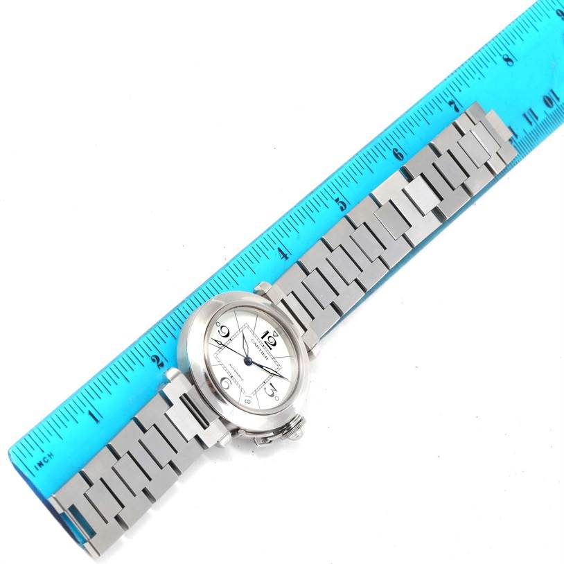The Cartier Pasha W31074M7 Women's Stainless Steel White Dial W31074M7 Women's Stainless Steel White Dial watch is shown from an overhead angle, displaying its face, dial, and metal bracelet, measured against a blue ruler.