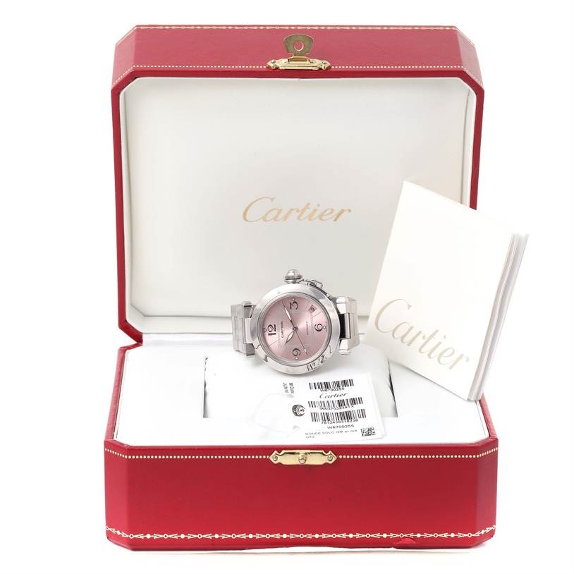 The Cartier Pasha W31075M7 Women's Stainless Steel Pink Dial W31075M7 Women's Stainless Steel Pink Dial watch is displayed head-on in its open box, with paperwork beside it.