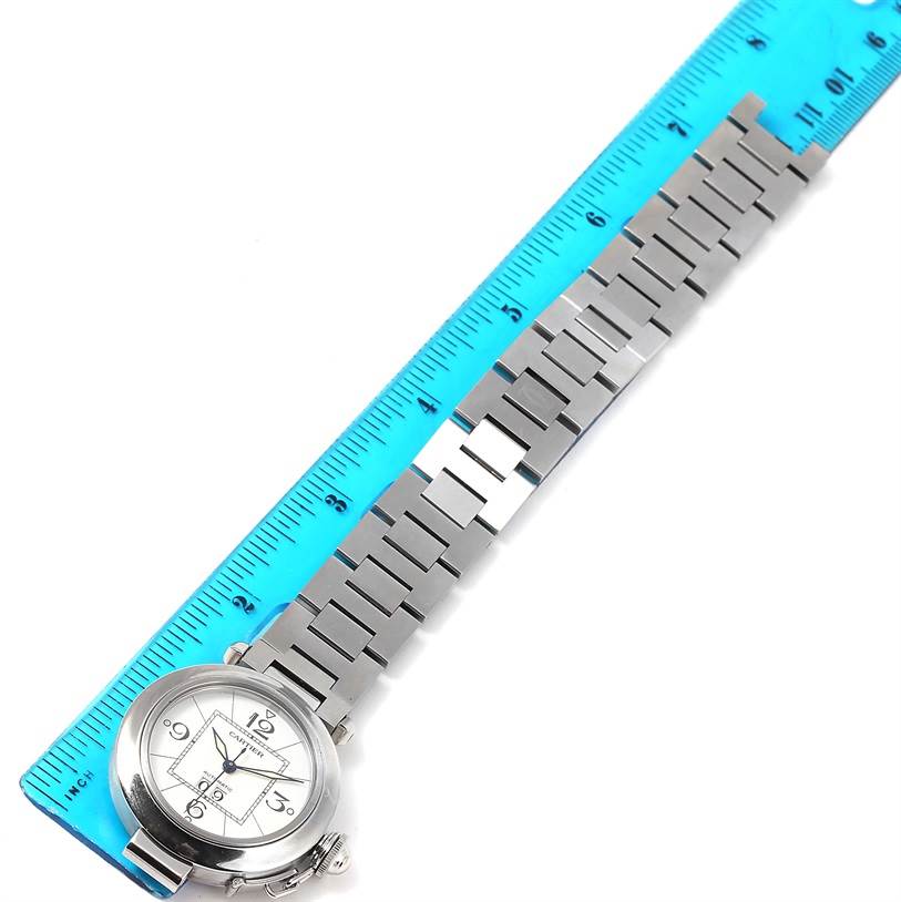 A Cartier Pasha W31055M7 Women's Stainless Steel White Dial W31055M7 Women's Stainless Steel White Dial watch is shown flat along a blue ruler, highlighting its face and metal bracelet.