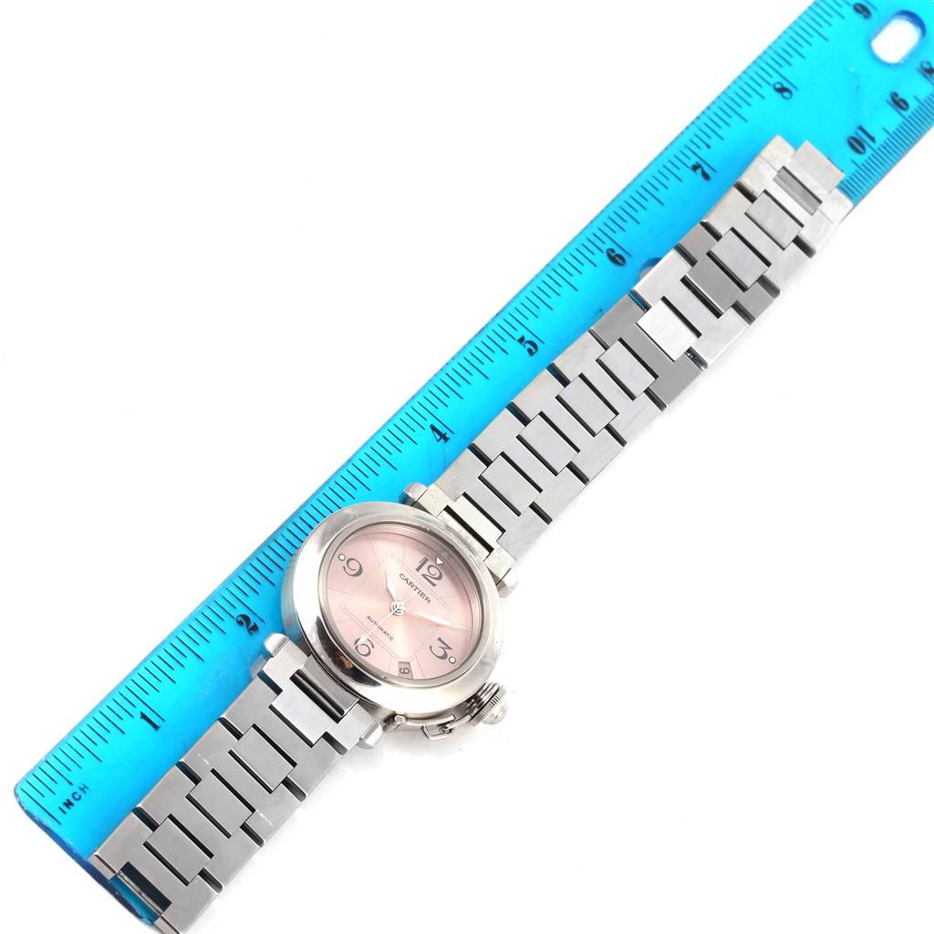 The Cartier Pasha W31075M7 Men
s Stainless Steel Pink Dial W31075M7 Men
s Stainless Steel Pink Dial watch is displayed flat with its metal bracelet fully extended and a blue ruler for scale.