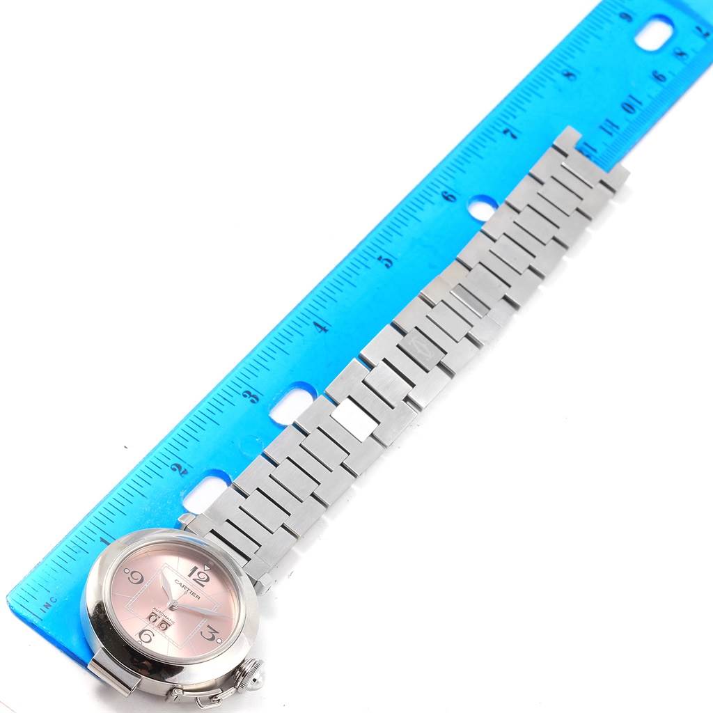 The Cartier Pasha W31058M7 Women's Stainless Steel Pink Dial W31058M7 Women's Stainless Steel Pink Dial watch, shown from the front angle, is alongside a ruler displaying its stainless steel bracelet.