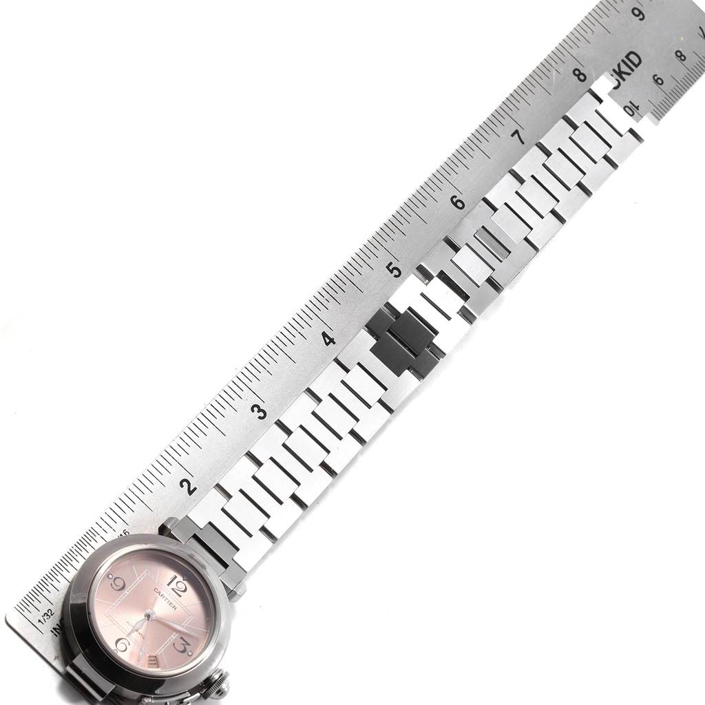 The image shows the face and part of the bracelet of a Cartier Pasha W31075M7 Men's Stainless Steel Pink Dial W31075M7 Men's Stainless Steel Pink Dial watch, with a measuring ruler alongside it.