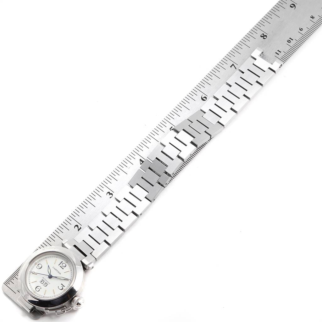 The Cartier Pasha W31044M7 Men's Stainless Steel White Dial W31044M7 Men's Stainless Steel White Dial watch is shown with its face and bracelet at an angle alongside a ruler for scale measurement.