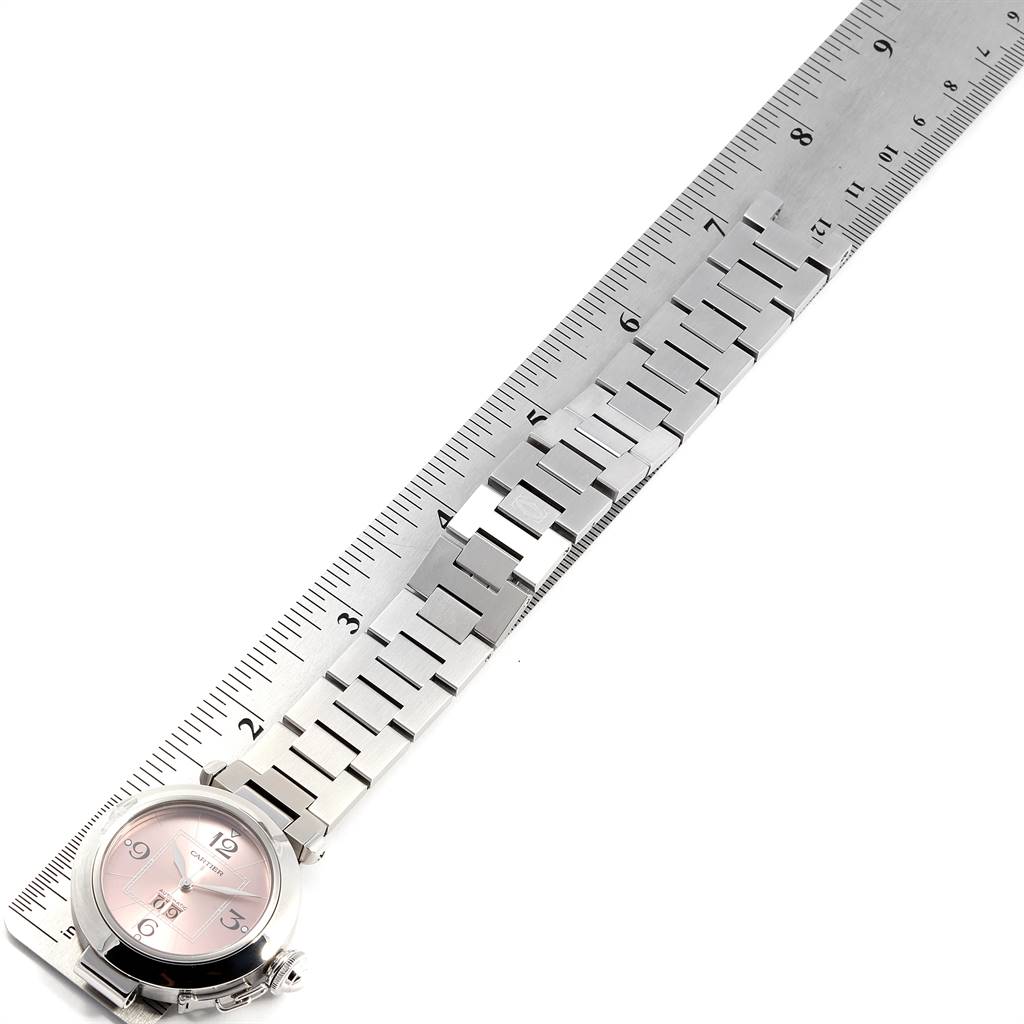 The Cartier Pasha W31058M7 Women
s Stainless Steel Pink Dial W31058M7 Women
s Stainless Steel Pink Dial watch is shown lying flat with its metal band alongside a ruler for measurement.