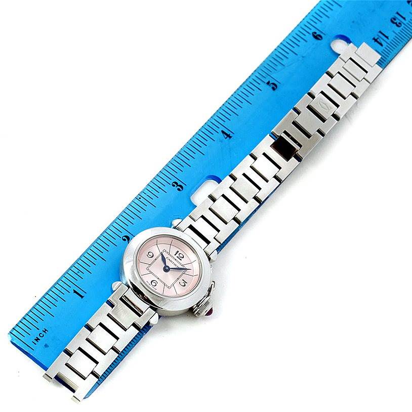 The Cartier Pasha W3140008 Women
s Stainless Steel Pink Dial W3140008 Women
s Stainless Steel Pink Dial watch is shown at a top-down angle with the face and metal bracelet visible, placed next to a blue ruler.