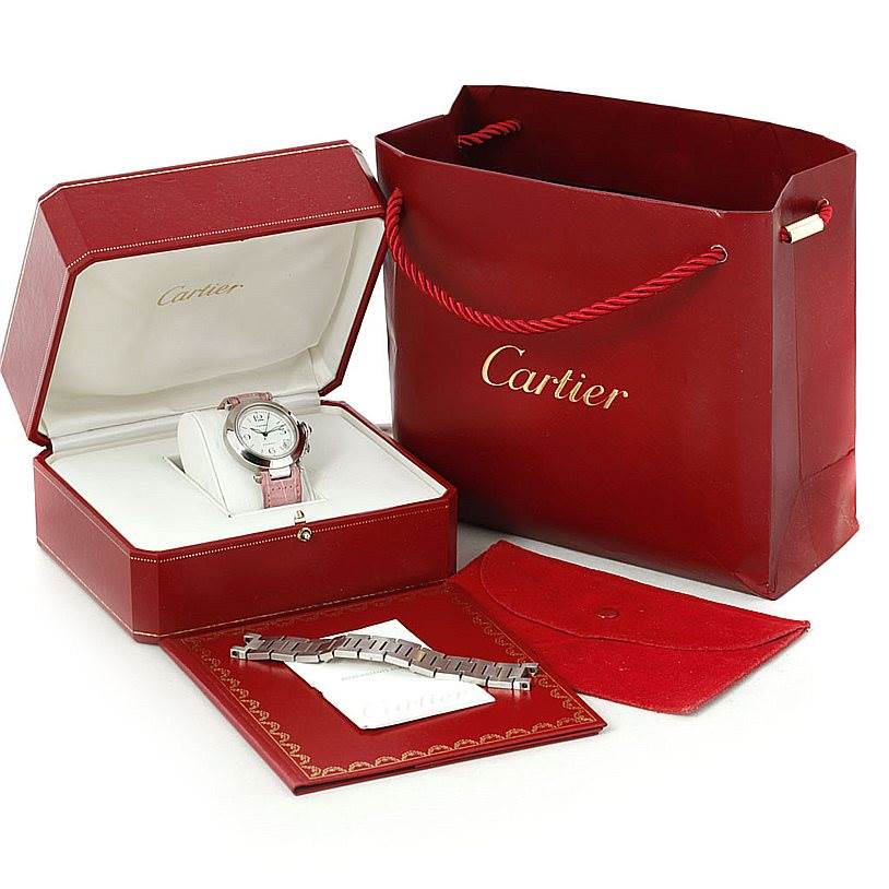 The image shows a Cartier Pasha W31015M7 Women's Stainless Steel White Dial W31015M7 Women's Stainless Steel White Dial watch with accessories including an extra bracelet, presented in a red box and shopping bag.