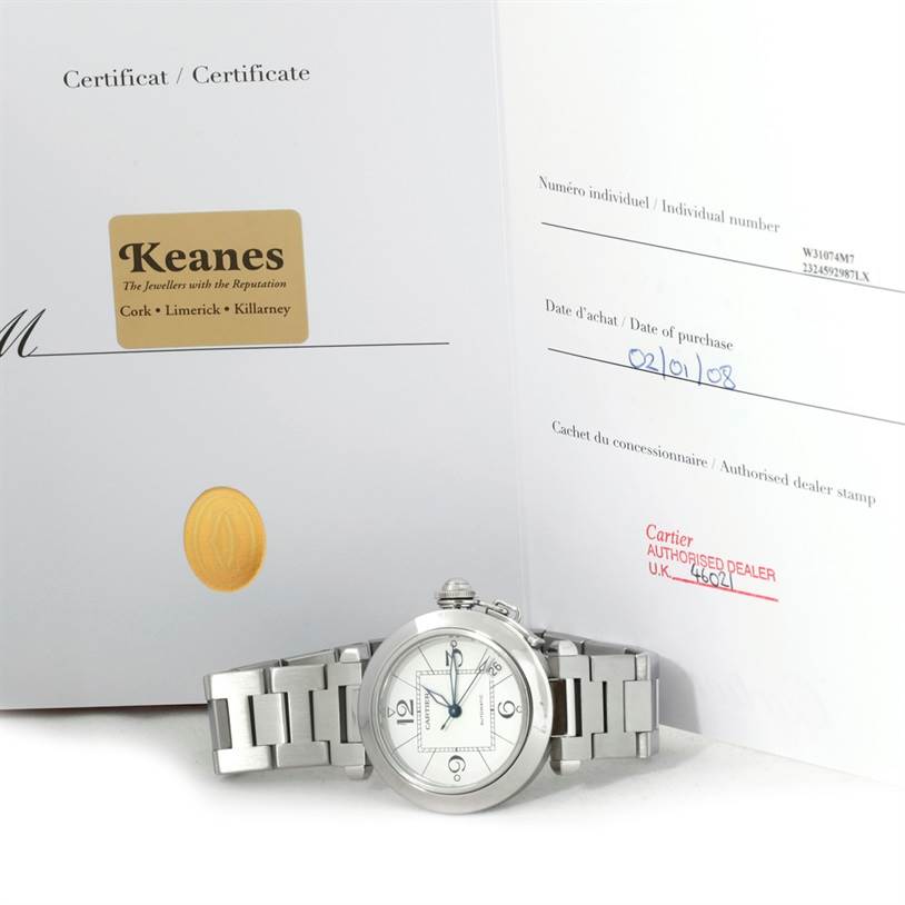 The image shows a Cartier Pasha W31074M7 Women's Stainless Steel White Dial W31074M7 Women's Stainless Steel White Dial watch from the front, with its certificate of authenticity in the background.
