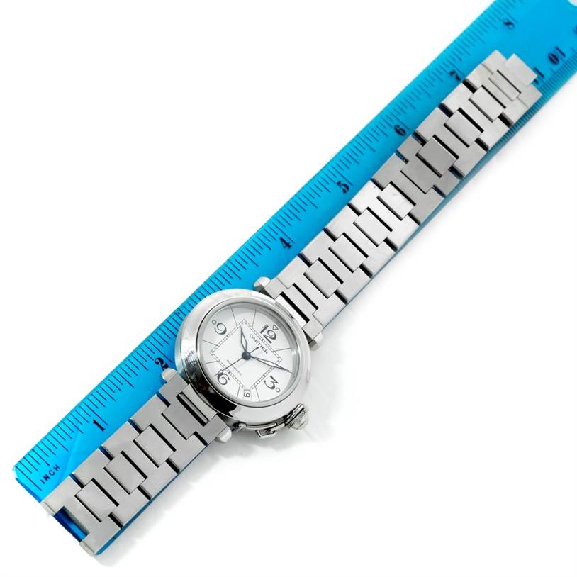 This top-down view shows the entire face and bracelet of the Cartier Pasha W31074M7 Women's Stainless Steel White Dial W31074M7 Women's Stainless Steel White Dial watch alongside a ruler for scale.