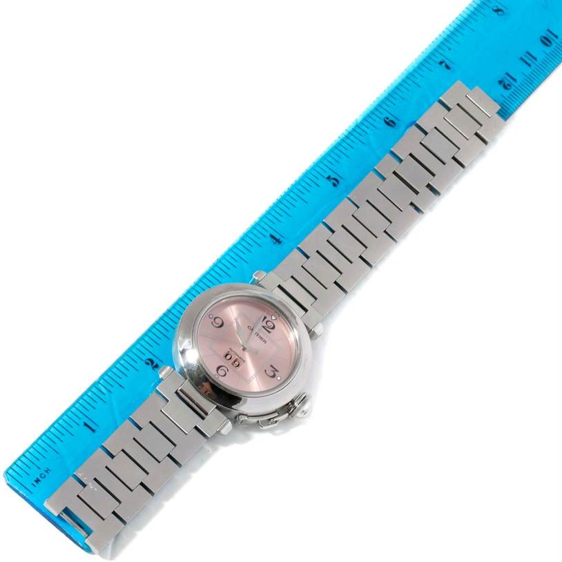 This Cartier Pasha 9791 Women
s Stainless Steel Pink Dial 9791 Women
s Stainless Steel Pink Dial watch is shown from a top-down angle, revealing its dial, case, and bracelet alongside a ruler for scale.
