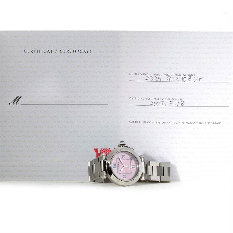 The image shows a Cartier Pasha W3108199 Women's Stainless Steel Pink Dial W3108199 Women's Stainless Steel Pink Dial watch laid flat on its bracelet with a certificate in the background.