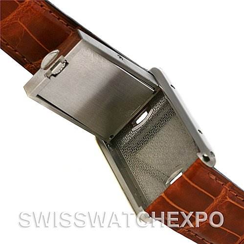 The image shows a close-up of the Tank Basculante model by Cartier with the case pivoted open, revealing its inner mechanism and brown leather strap.