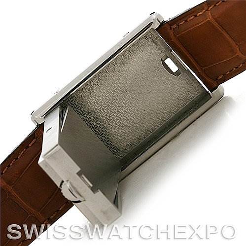 The image shows the Tank Basculante watch by Cartier with the case flipped open, revealing its inner mechanism, and a brown leather strap.