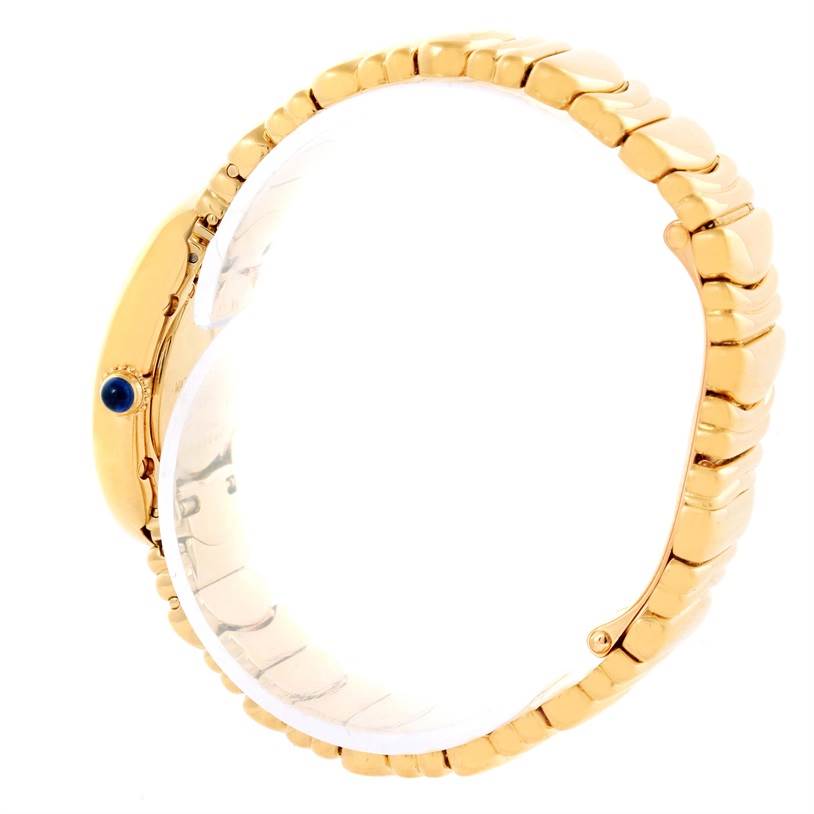 Side view of a Cartier Baignoire Women's Yellow Gold Silver Dial Women's Yellow Gold Silver Dial watch showing the gold bracelet and crown with a blue cabochon.