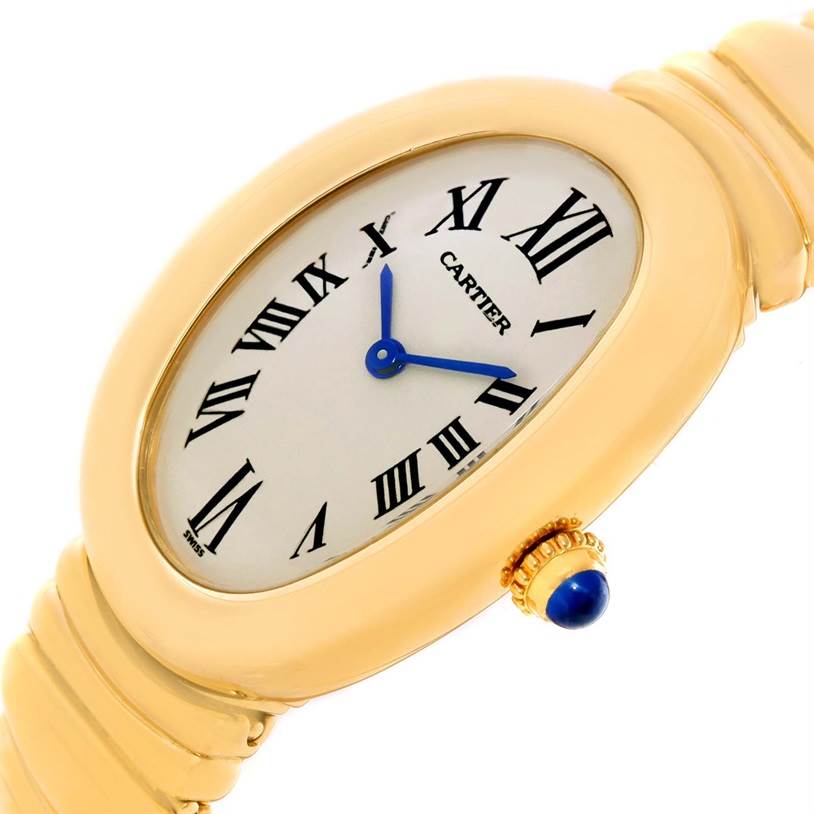 The image shows a close-up, angled view of the Cartier Baignoire Women's Yellow Gold Silver Dial Women's Yellow Gold Silver Dial watch, displaying its face, blue hands, Roman numerals, and part of its gold bracelet.