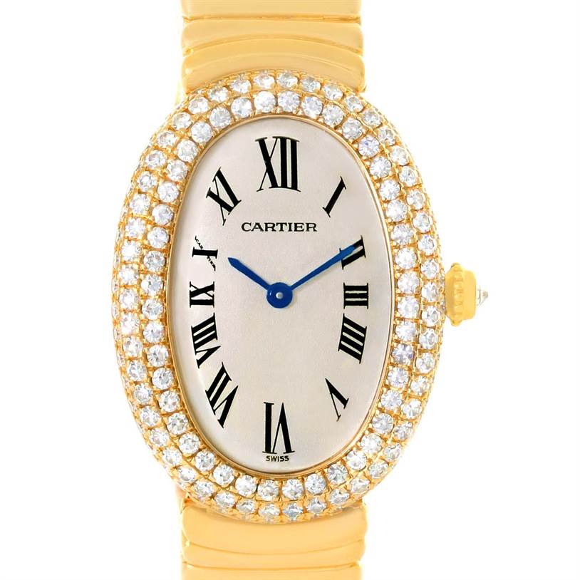 The image shows a close-up of a Cartier Baignoire 1950 Women
s Yellow Gold Silver Dial 1950 Women
s Yellow Gold Silver Dial watch, focusing on its diamond-encrusted oval face and gold strap.