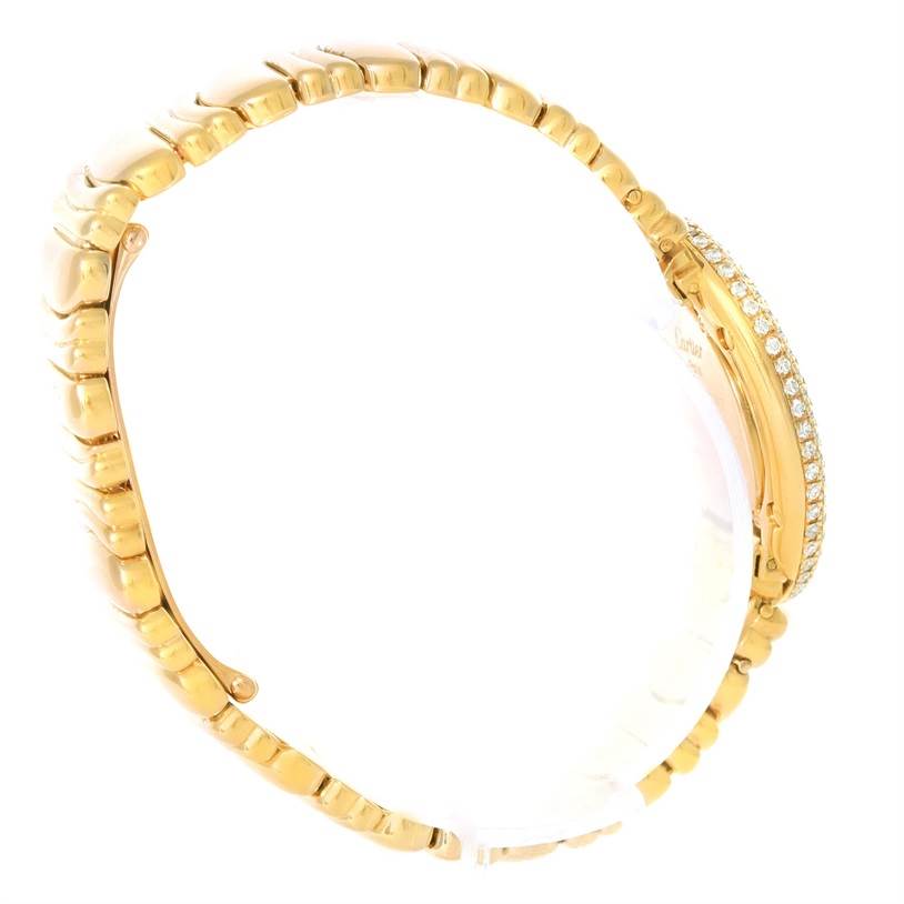 The image shows a side angle of the Baignoire model watch by Cartier, highlighting its gold bracelet and diamond-studded case.