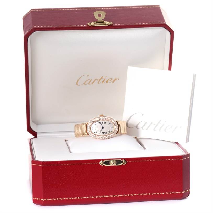 The Cartier Baignoire 1950 Women
s Yellow Gold Silver Dial 1950 Women
s Yellow Gold Silver Dial watch is shown in an open red box, displaying its face and bracelet, along with Cartier brand documentation.