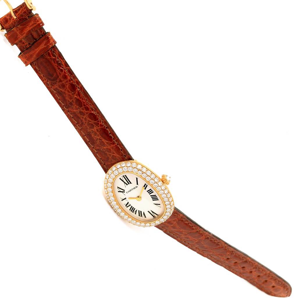 The Cartier Baignoire 1954 Women
s Yellow Gold Silver Dial 1954 Women
s Yellow Gold Silver Dial watch is shown flat with a brown leather strap and diamond-studded oval face.