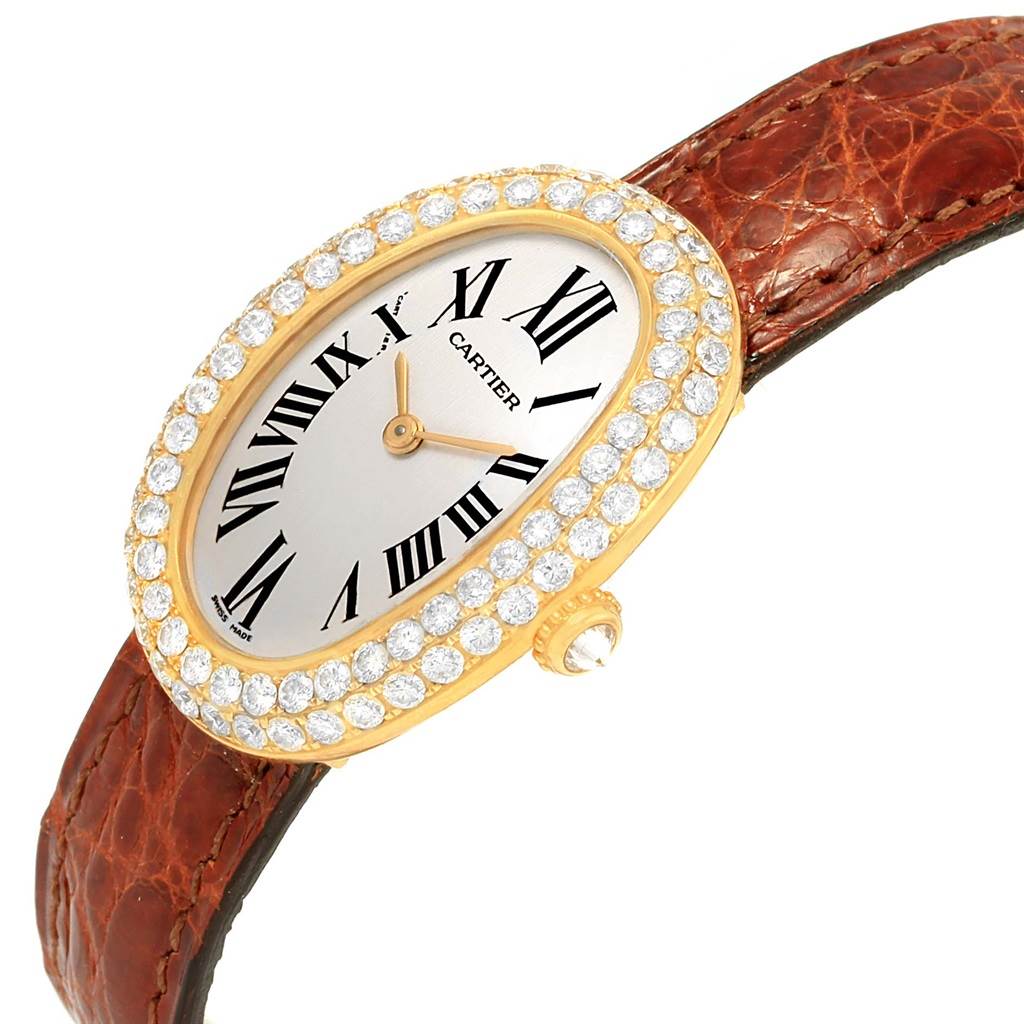  The Cartier Baignoire 1954 Women
s Yellow Gold Silver Dial 1954 Women
s Yellow Gold Silver Dial watch is shown at an angle highlighting the oval face, diamond bezel, gold casing, and brown leather strap.