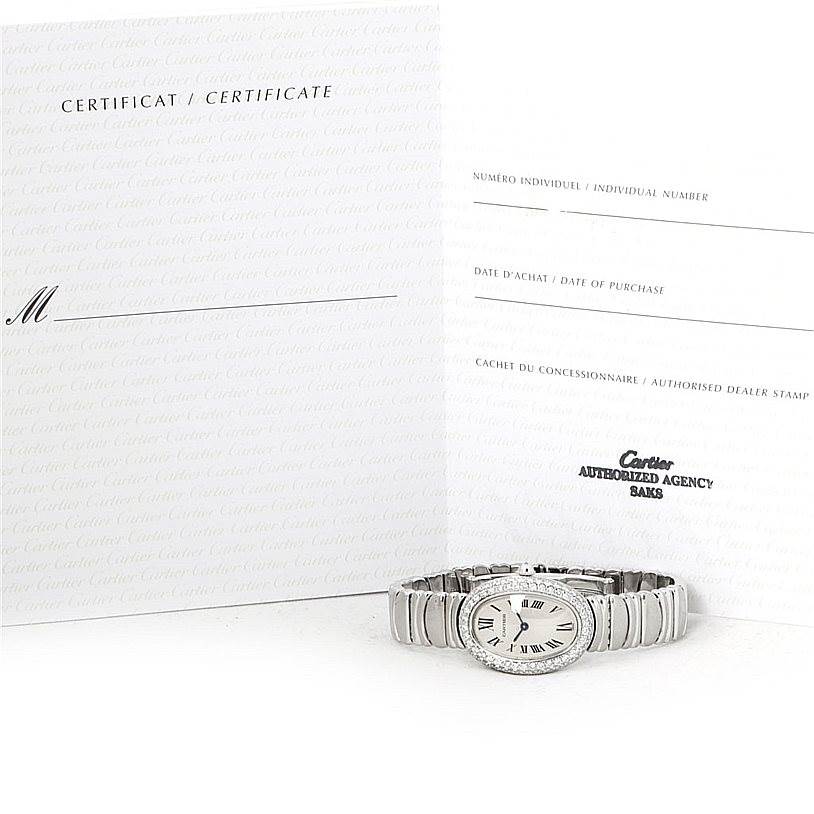 The image shows a Cartier Baignoire WB5097L2 Women's White Gold Silver Dial WB5097L2 Women's White Gold Silver Dial watch lying flat with its certificate of authenticity displayed behind it.