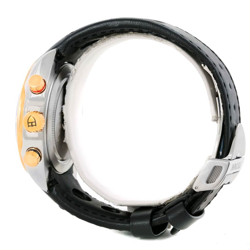 The image shows a Tudor Grantour 20551N Men's Steel and Gold (two tone) Black Dial 20551N Men's Steel and Gold (two tone) Black Dial watch from a side angle, highlighting its buttons, crown, and leather strap with a clasp.