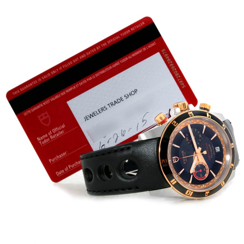 The image shows a Tudor Grantour 20551N Men's Steel and Gold (two tone) Black Dial 20551N Men's Steel and Gold (two tone) Black Dial watch at an angle highlighting its face, strap, and side buttons, along with its guarantee card.