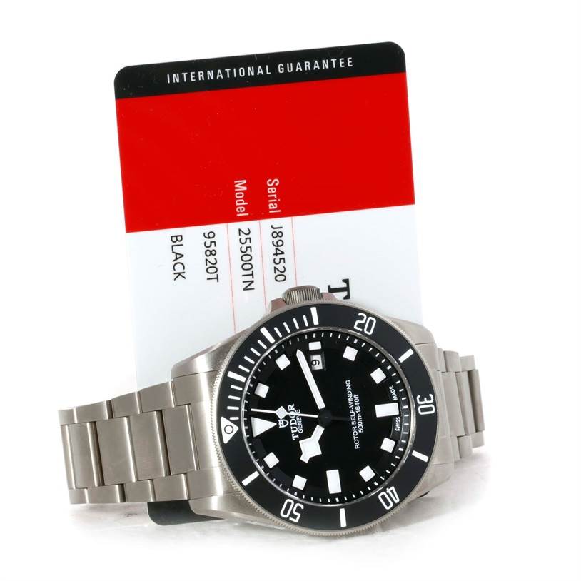 The image shows a Tudor Pelagos 25500TN Men's Titanium Black Dial 25500TN Men's Titanium Black Dial watch from a top-down angle, along with its international guarantee card.