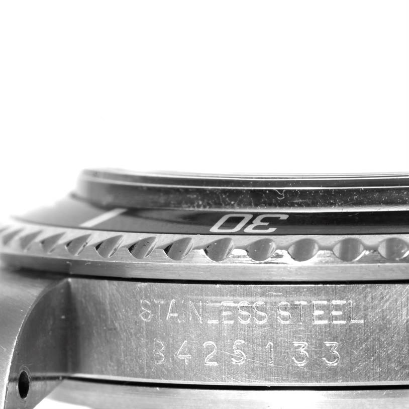This is a close-up, side view of the bezel and case of a Tudor Submariner 79090 Men's Stainless Steel Black Dial 79090 Men's Stainless Steel Black Dial watch, showing the etchings and part of the bezel edge.