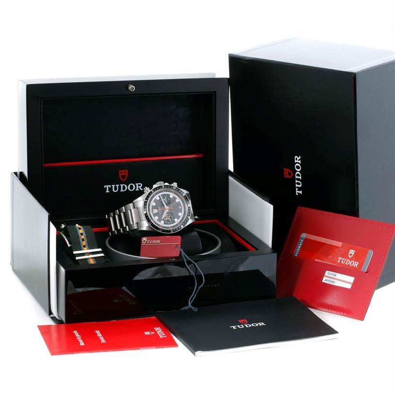 The image shows a Tudor Heritage Chrono 70330N-95740 Men's Stainless Steel Grey Dial 70330N-95740 Men's Stainless Steel Grey Dial watch, its box, additional strap, warranty card, and manuals, viewed from the front.
