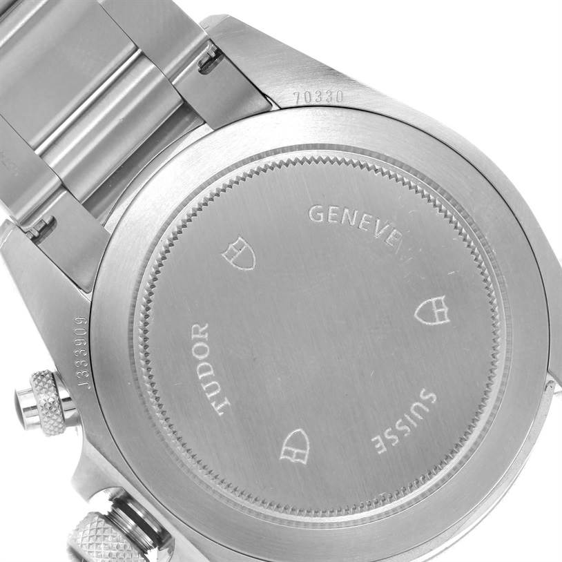 The image shows a close-up view of the case back of the Tudor Heritage Chrono 70330N-95740 Men's Stainless Steel Black Dial 70330N-95740 Men's Stainless Steel Black Dial watch, featuring engravings and part of the bracelet.