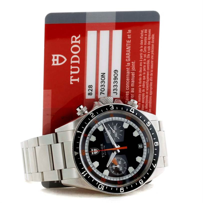The image shows a front view of the Tudor Heritage Chrono 70330N-95740 Men's Stainless Steel Black Dial 70330N-95740 Men's Stainless Steel Black Dial watch along with its guarantee card.