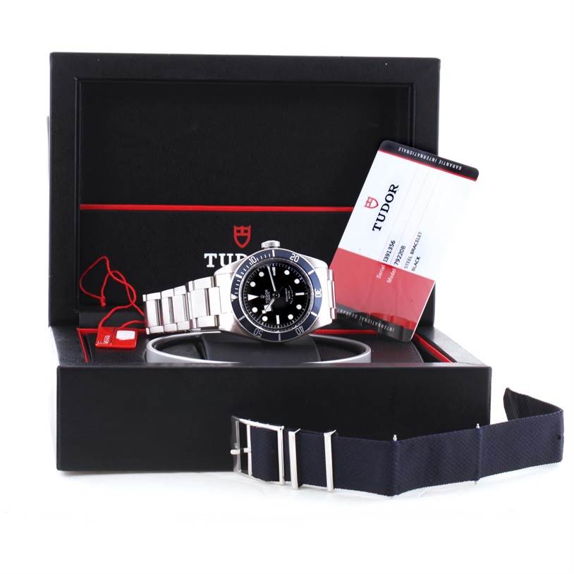 The image shows a Tudor Heritage Black Bay 79220 Men's Stainless Steel Black Dial 79220 Men's Stainless Steel Black Dial watch, presented in its box with warranty cards and an additional strap.