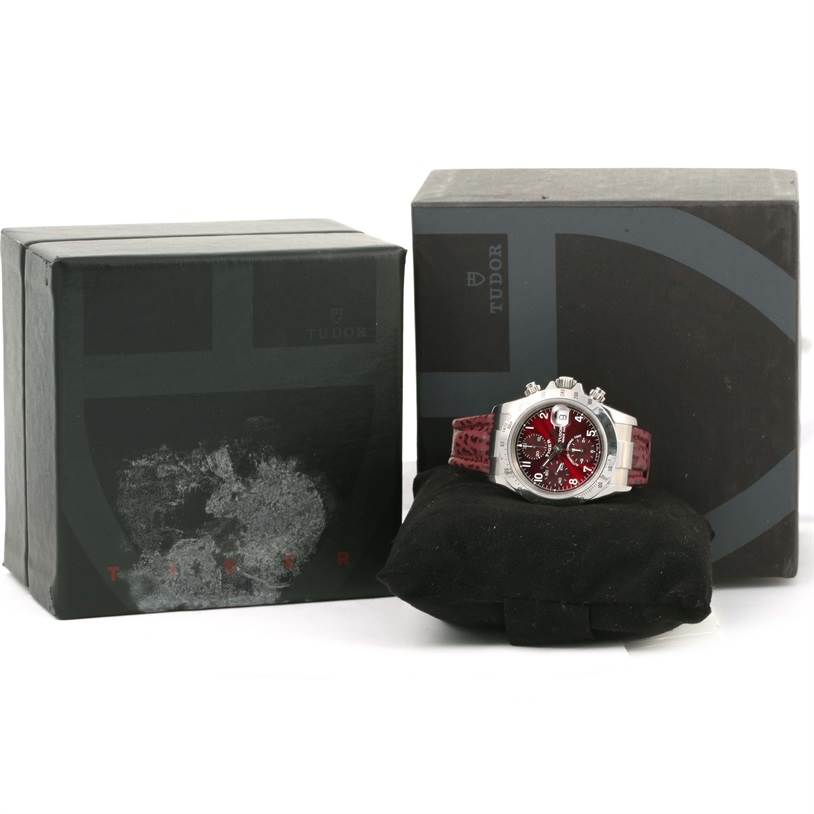 This image shows a Tudor Tiger 79280 Men's Stainless Steel Burgundy Dial 79280 Men's Stainless Steel Burgundy Dial model watch from a front angle along with its boxes.