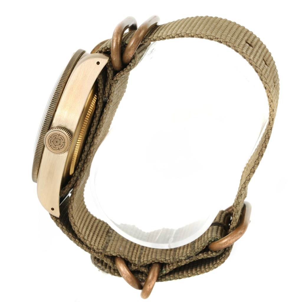 The image shows a side view of the Tudor Heritage Black Bay 79250 Men's Bronze Brown Dial 79250 Men's Bronze Brown Dial watch, highlighting the case, crown, and khaki nylon strap with metal rings.