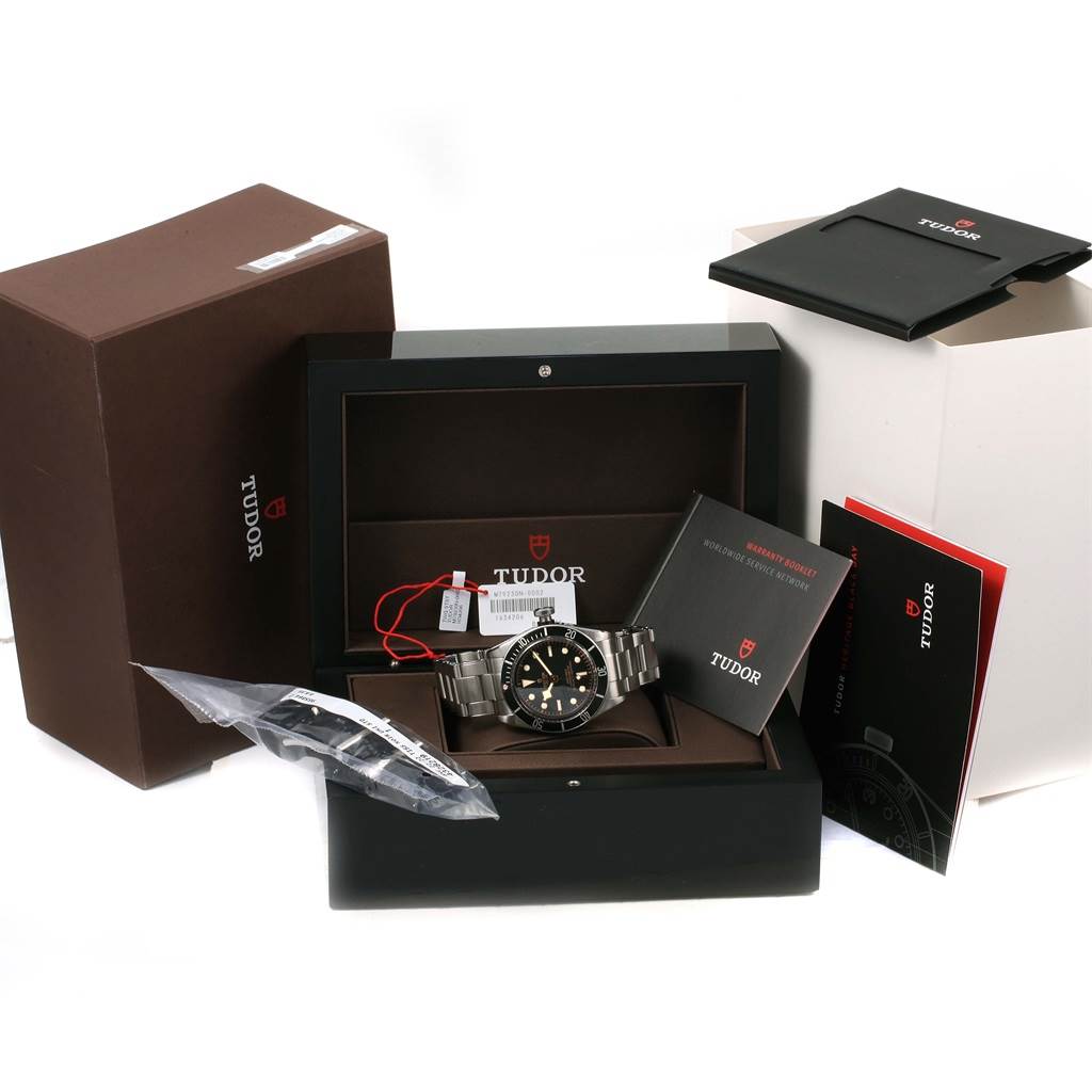 The image shows a Tudor Heritage Black Bay 79230N Men's Stainless Steel Black Dial 79230N Men's Stainless Steel Black Dial watch with its packaging, manuals, and extra links at an angle displaying the front and accessories.