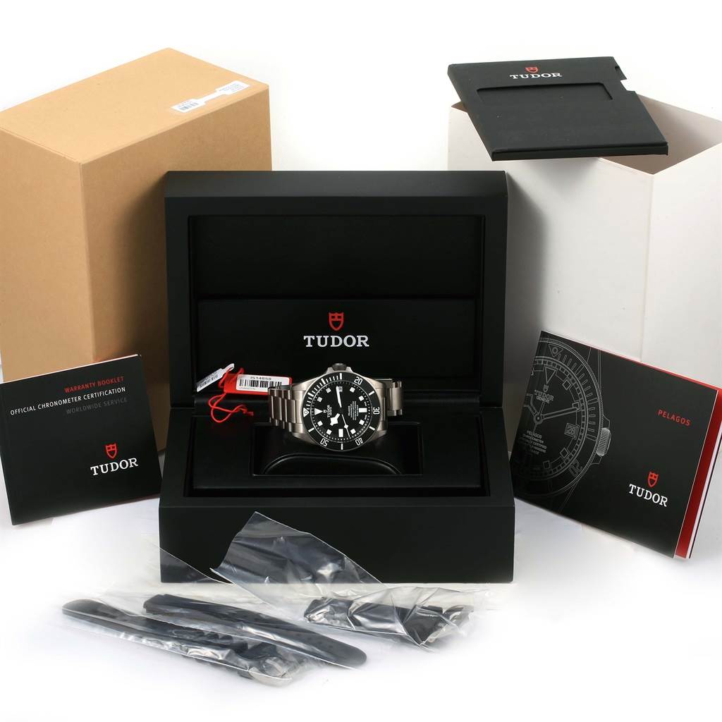 The image shows a Tudor Pelagos 25600TN Men's Titanium Black Dial 25600TN Men's Titanium Black Dial watch with its box, warranty booklets, and additional straps.