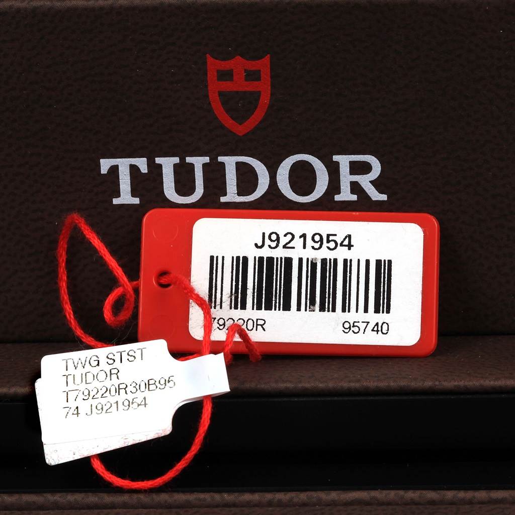 The image shows a close-up of a barcode tag and label for the Tudor Heritage Black Bay 79220R Men's Stainless Steel Black Dial 79220R Men's Stainless Steel Black Dial model, hanging from its box.