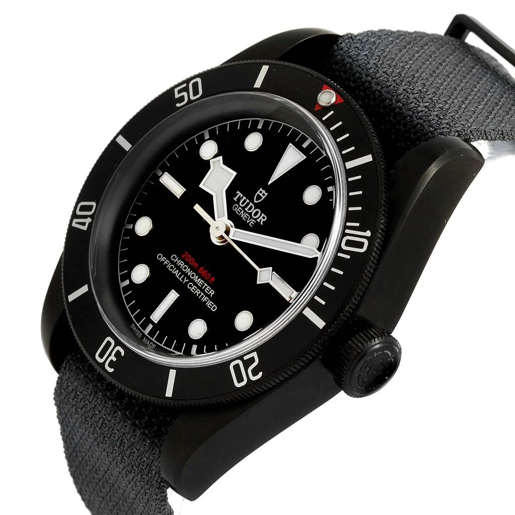 This image shows the Tudor Heritage Black Bay 79230DK Men's Stainless Steel Black Dial 79230DK Men's Stainless Steel Black Dial watch at a tilted angle, highlighting the dial, bezel, and fabric strap.