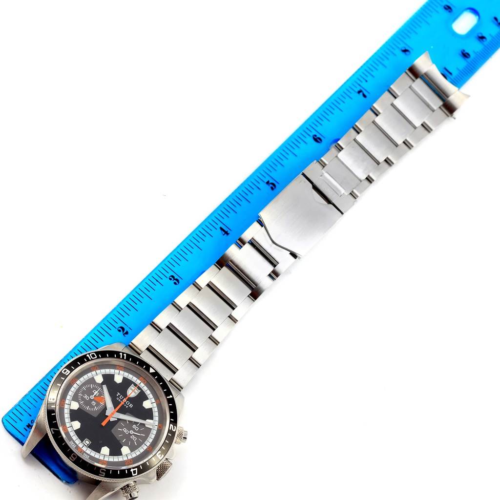 The image shows a Tudor Heritage Chrono 70330N Men's Stainless Steel Grey Dial 70330N Men's Stainless Steel Grey Dial watch placed flat with its stainless steel bracelet extended and measured against a blue ruler.