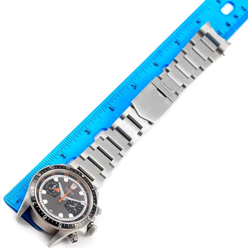 The Tudor Heritage Chrono 70330N Men's Stainless Steel Grey Dial 70330N Men's Stainless Steel Grey Dial watch is shown laying flat with a measurement ruler, displaying its face and metal band.