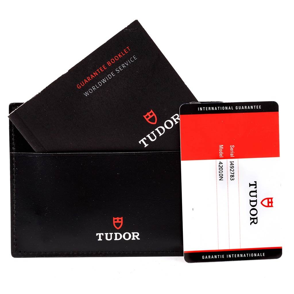 The image shows the warranty card, booklet, and black leather sleeve for the Tudor Fastrider 42010N Men
s Stainless Steel Green Dial 42010N Men
s Stainless Steel Green Dial model.