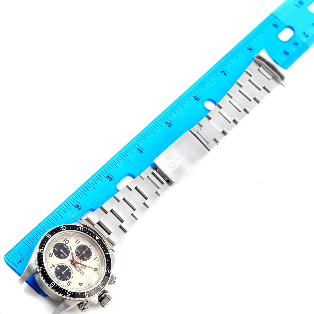 The Tudor Tiger 79270 Men's Stainless Steel White Dial 79270 Men's Stainless Steel White Dial model watch is shown from a top-down angle, displaying the face and metal bracelet next to a ruler.