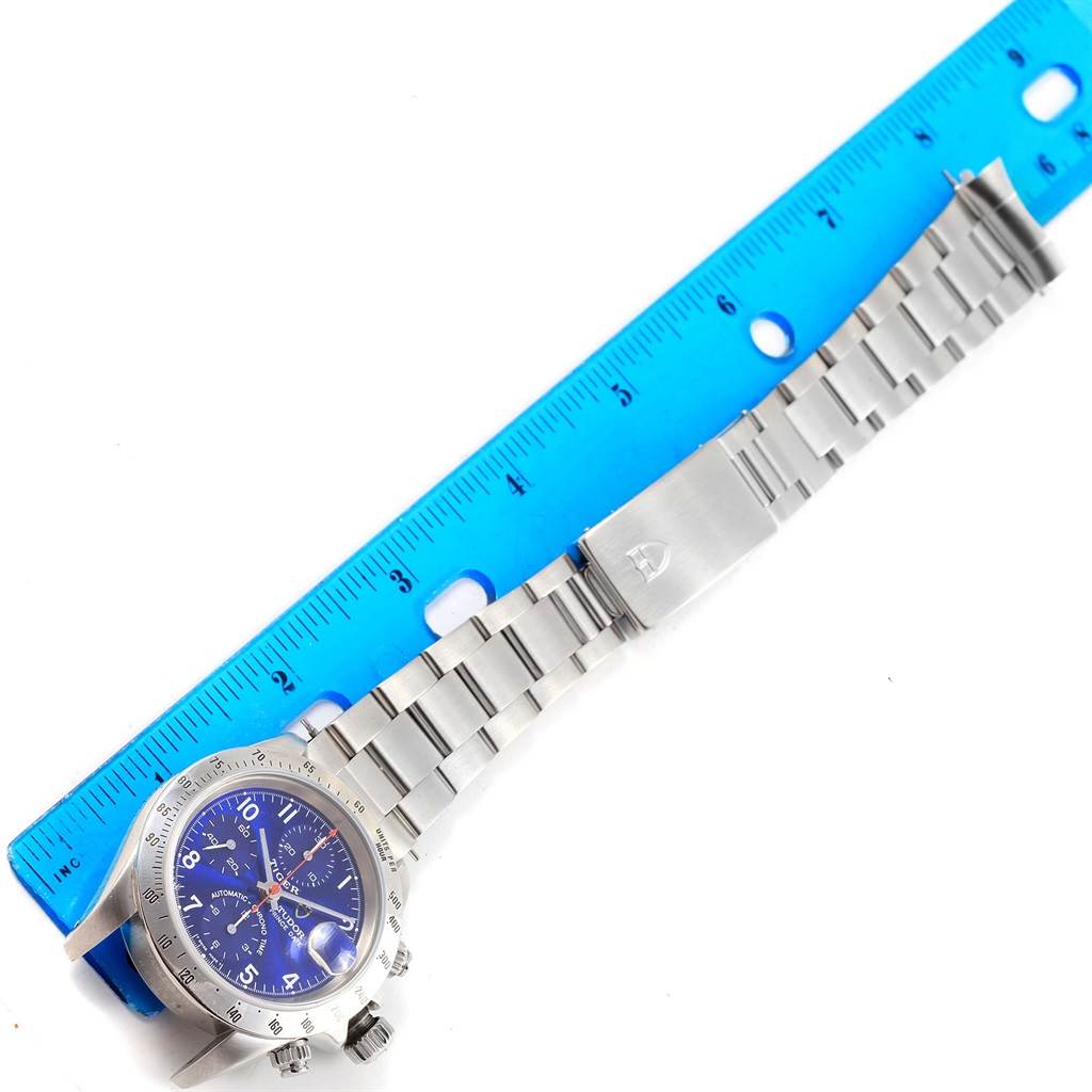 The image shows a Tudor Tiger 79280 Men's Stainless Steel Blue Dial 79280 Men's Stainless Steel Blue Dial model watch laid flat, featuring its face, bezel, and metal bracelet, next to a blue ruler.