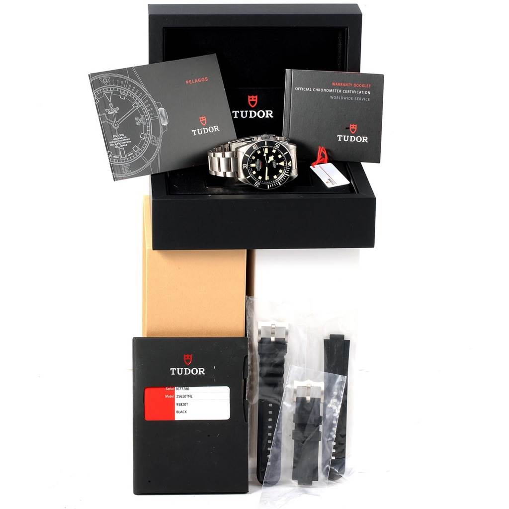 This image shows the Tudor Pelagos 25610TNL Men's Titanium Black Dial 25610TNL Men's Titanium Black Dial watch at a front angle, along with its box, booklets, and additional strap accessories.