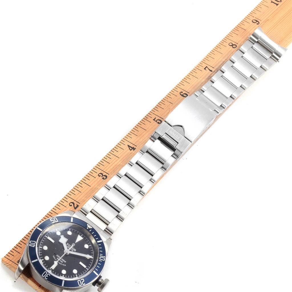 The Tudor Heritage Black Bay 79220B Men
s Stainless Steel Black Dial 79220B Men
s Stainless Steel Black Dial watch is shown from the front, displaying the face, bezel, and stainless steel bracelet against a ruler.