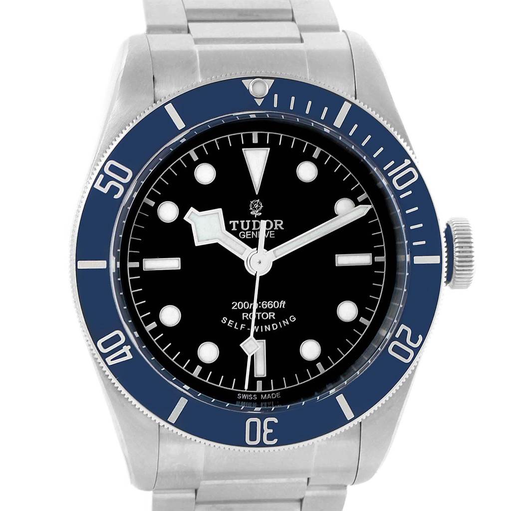 The image shows a front view of the Tudor Heritage Black Bay 79220B Men
s Stainless Steel Black Dial 79220B Men
s Stainless Steel Black Dial watch, featuring its dial, bezel, and a portion of the bracelet.