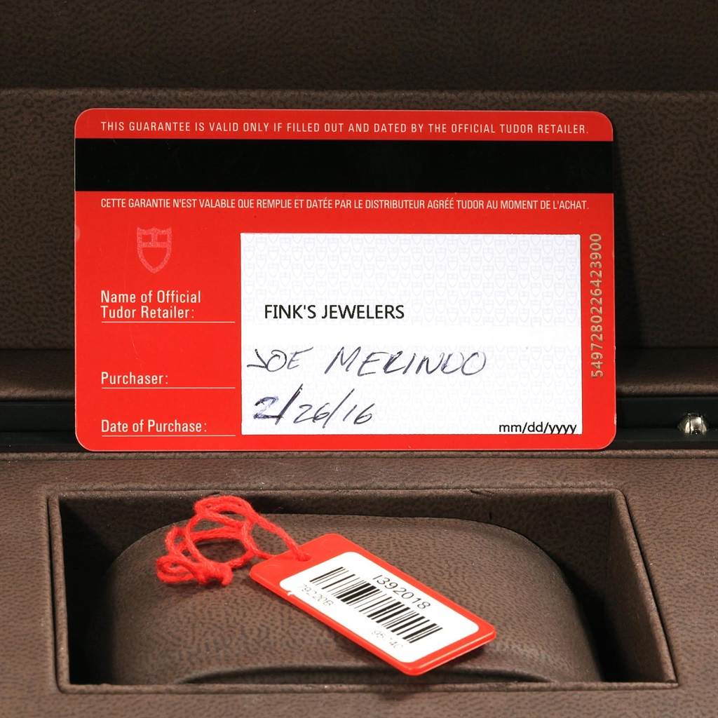 The image shows a warranty card and a retail tag for the Tudor Heritage Black Bay 79220B Men
s Stainless Steel Black Dial 79220B Men
s Stainless Steel Black Dial model.