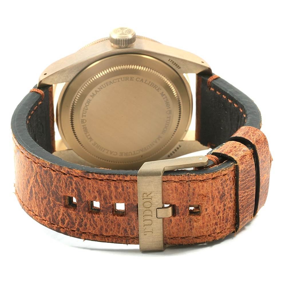 This image shows the back view of a Tudor Heritage Black Bay 79250 Men's Bronze Brown Dial 79250 Men's Bronze Brown Dial watch, focusing on the case back, crown, and leather strap with the "TUDOR" engraved buckle.